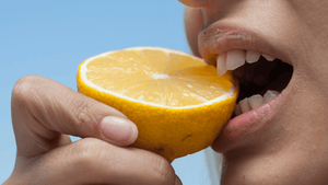 close up of a women with her teeth and eating a lemon