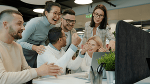 A bright, candid shot of a group of coworkers laughing together in a relaxed office setting