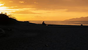 A person on a beach watching the calm sunset 